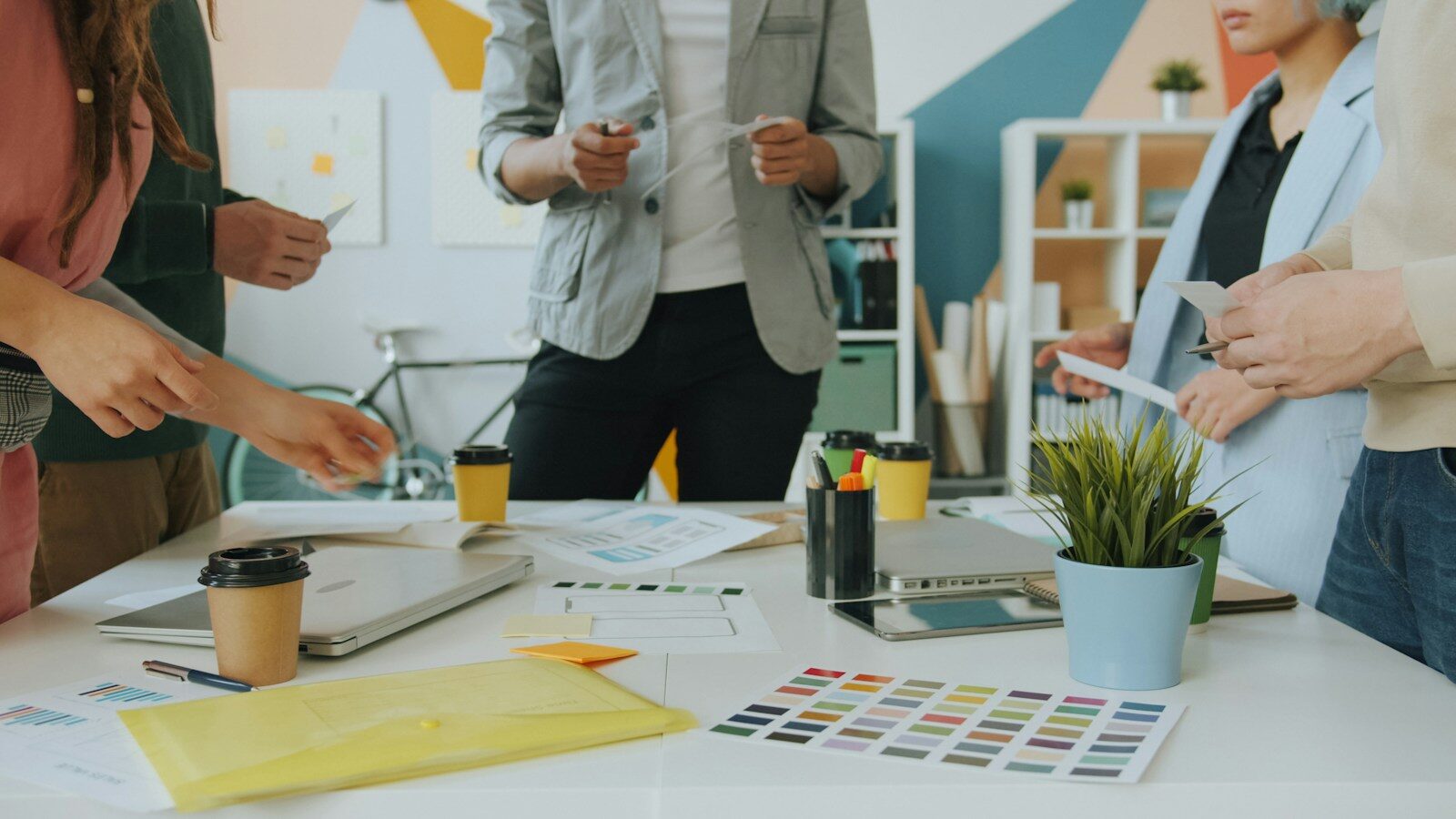 Photo by Vitaly Gariev A group of people collaborating around a table with design documents and coffee